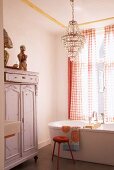 Badezimmer mit Vintage-Schrank, Kristallleuchter und freistehender Badewanne