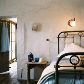 Rustic bedroom with old metal bed and wooden stool used as bedside table