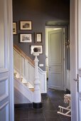 Stairwell with white wooden stairs and collection of pictures on wall