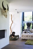 Detail of living room with open fireplace, animal skull and patterned couch with scatter cushions