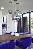Dining table, indigo armchairs and spherical chrome pendant lamps