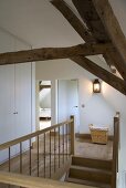 Landing with wooden floor, rustic roof beams and large laundry basket