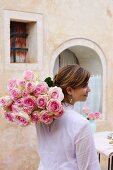 A woman carrying a bunch of roses to a garden table