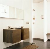 Moderne Hängeschränke aus dunklem Holz neben runde Nasszelle im Bad mit schwarzen Bodenfliesen