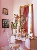 Ein rosafarbenes Zimmer mit rosa Kosmetiktisch und vergoldeter Spiegel