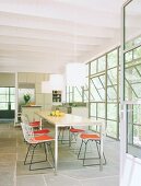 Lichterfülltes Esszimmer mit langem Esstisch und moderner Küche mit Küchenblock im Hintergrund