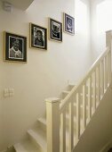 Treppenaufgang mit weisslackierter Holztreppe und einer Portraitsammlung