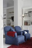 Blick vom Wohnzimmer mit behaglichen, blauen Sesseln in den Essraum mit Einbauschrank