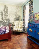 Gemütliche Zimmerecke mit bunter Kommode sowie antikem Holzbett und Ohrensessel, an der Wand eine Renaissancetapete
