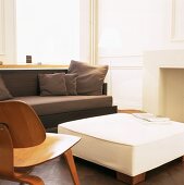 Ausschnitt eines Wohnraums mit großem Polsterhocker und Sofa neben einem Eames Chair