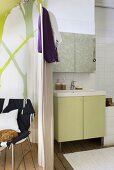 Das kleine, offene Badezimmer mit Vintagewaschtisch ist durch einen Paravent vom Wohnraum getrennt