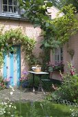 Garten und Terrasse eines schönen Wohnhauses mit rosa gestrichener Ziegelsteinfassade und türkiser Tür