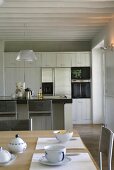 Moderne Küche unter weisser Balkendecke im offenen Wohnraum