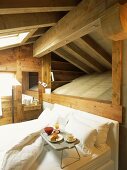 Bett mit Frühstückstablett unter Dachschräge eines Holzhauses