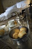 Frühstückstablett mit Gebäck, Tassen und Silbergeschirr auf Bett