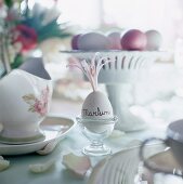 A breakfast egg as a place card on a table laid for Easter Day