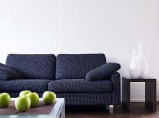 Wohnraum mit grauem Sofa, Beistelltisch mit Vasen & Couchtisch dekoriert mit Äpfeln