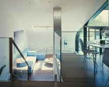 A cool, modern house with a dining area on a mezzanine floor and a view of a sofa in the living room