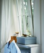 Kästchen mit Bürste & Kette am Fenster in einem Schlafzimmer
