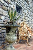 Agave in an antique plant container and rusty bench in front of natural stone facade