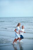 Mädchen und Junge laufen am Strand