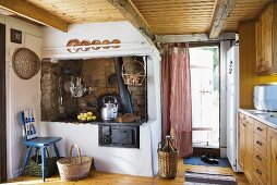 Alter Küchenofen mit Kaminabzug und Holzdecke im ländlichen Wochenendhaus