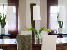 weiße Lampenschirme über Holztisch und Blumendeko