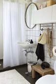 Waschbecken mit Spiegel an weissgefliesster Wand und Duschvorhang