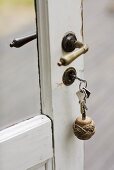A glass door with a white frame and a metal handles with bunch of keys in the lock