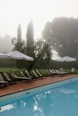 Foggy morning -- poolside with lounge chairs and sun umbrellas