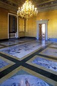Messingkerzenleuchter im Schlosssaal mit bemaltem Steinboden und goldener Wand
