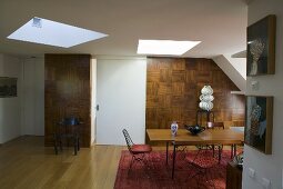 Open living room with skylights and dining area in front of a wood paneled wall