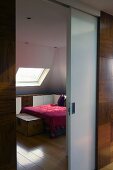 Half open sliding door with a view of a bed and a skylight