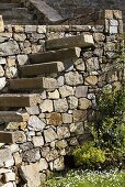 Overhanging stairs made of block of stone on a natural stone wall
