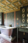 A vintage bathtub on a pedestal with wall taps in a painted room