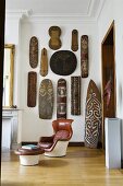 A living room in an old house - a leather chair with a foot stool with an African art collection on a wall