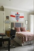 A boy's room with the English national flag hanging above the bed and a black swivel chair in front of a desk
