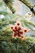 Sternförmige Weihnachtsdeko aus weißem Filz am Tannenzweig