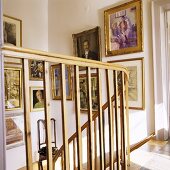 A view through a wooden banister in a stairway with pictures on the wall