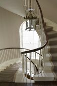 Chandelier in a stair well in a curved staircase with carpet runners