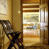 Gelber Vorraum mit antikem Stuhl und offene Tür mit Blick auf grauem Sessel mit gepolstertem Fussschemel