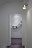 A view through an open door onto a curved bookshelf on a white wall