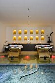 A massage room with a pool - wooden loungers in front of a wall niche and burning candles