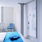 Blaue Tagesdecke auf Bett vor Metallstütze und Sessel im Rokokostil in Zimmerecke