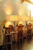 Illuminated bar tables - designer bar tables with stools and floor lamps in front of a natural stone wall