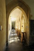 A view through a Gothic pointed archway along a long church corridor lined with bar tables
