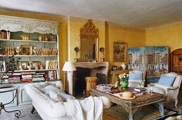 A yellow-painted living room in a country house with a sofa and a and coffee table in front of a fireplace