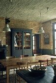 A rustic dining room with a straw ceiling and a dark grey cabinet in front of a brick wall