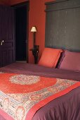 Bett mit orientalischer Tagesdecke und ziegelroter Wand
