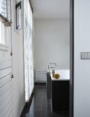 Blick ins Designer Bad auf Standarmatur vor Badewanne und graue Bodenfliesen